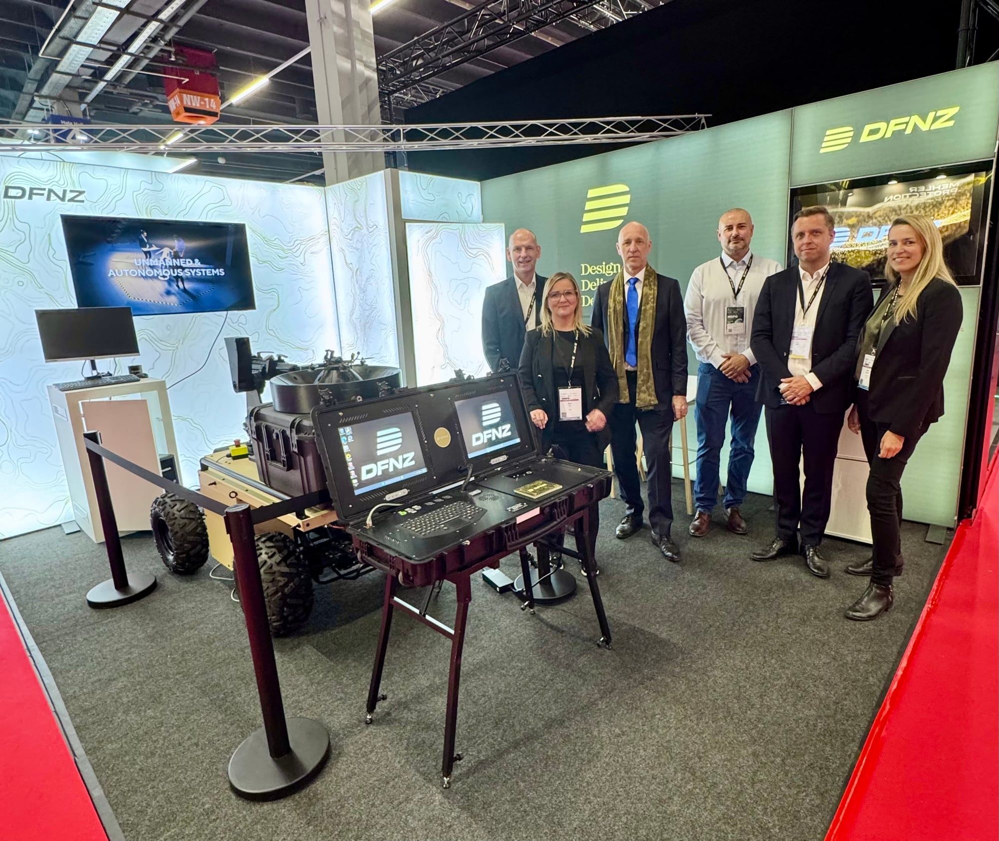 The DFNZ stand at MSPO 2026 in Kielce: an unmanned ground vehicle and a rugged dual-screen control console, with six people standing behind them in front of a display reading "Unmanned & Autonomous Systems".